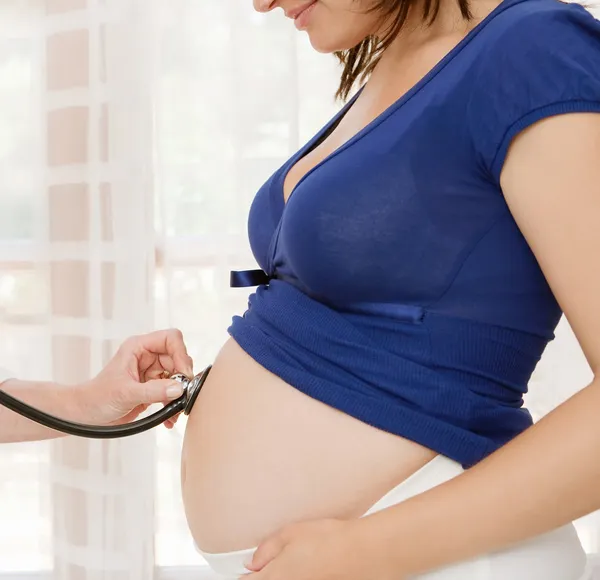 Donna incinta e medico utilizza uno stetoscopio per ascoltare — Foto Stock