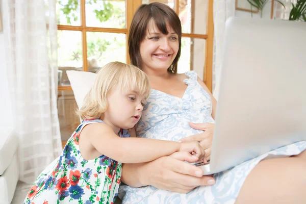 Mãe grávida e filha infantil com laptop — Fotografia de Stock