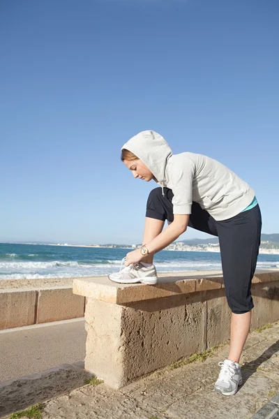 Mujer inclinándose para atar sus cordones de zapatos — Foto de Stock