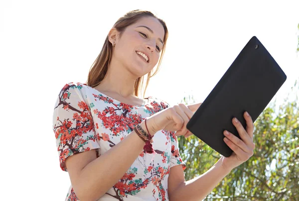 Mulher em um parque usando um tablet digital — Fotografia de Stock