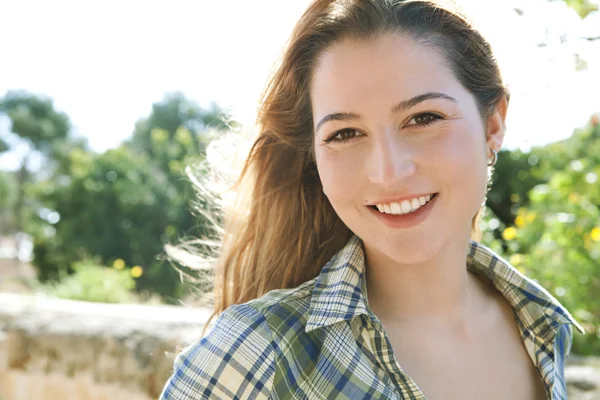 Woman smiling at the camera in a park — Stock Photo, Image