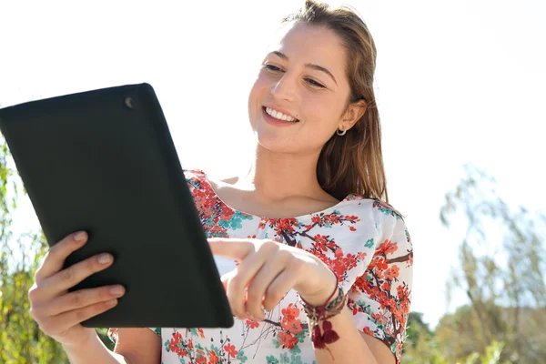 Mulher em um parque usando um tablet digital — Fotografia de Stock