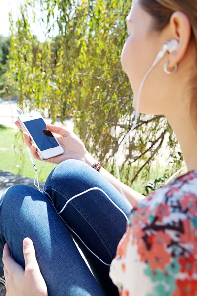 Femme dans un parc tenant un téléphone intelligent — Photo