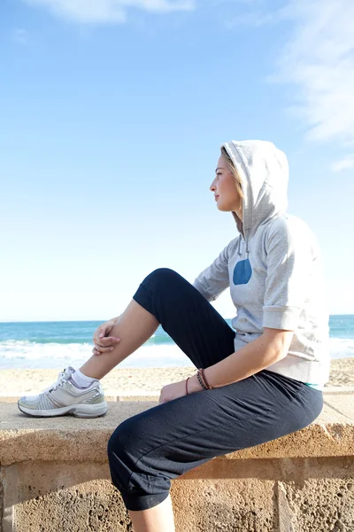 Mujer sentada junto a una playa — Foto de Stock