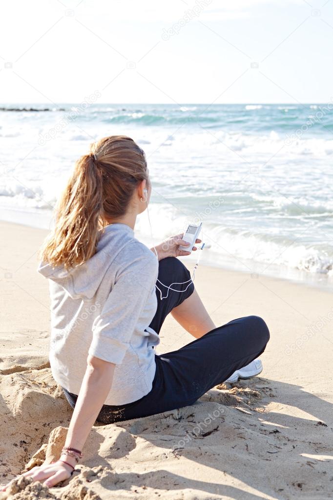 Woman sitting on a white sand beach shore