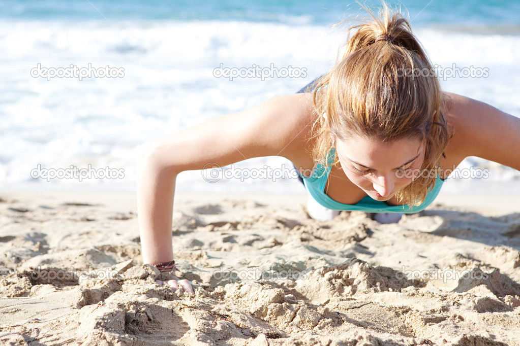Woman doing push ups exercises on the beach