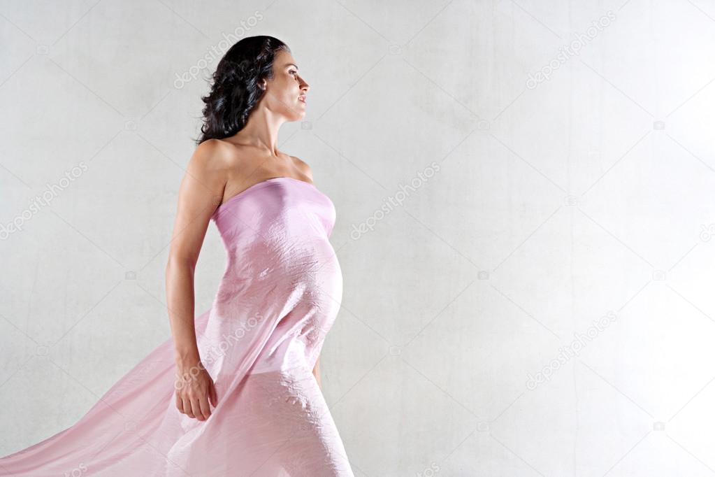 Strong pregnant woman wrapped in pink silk