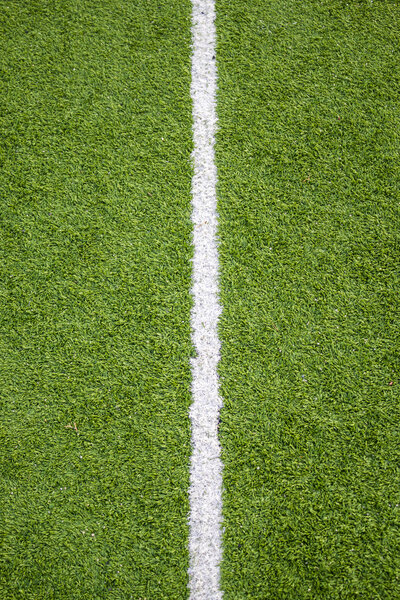 Белая линия на траве футбольного поля
