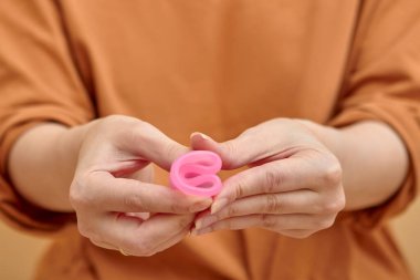 Genç kadın ellerinin regl kupasını katlaması. Kadın sağlığı konsepti, sıfır atık alternatif. 