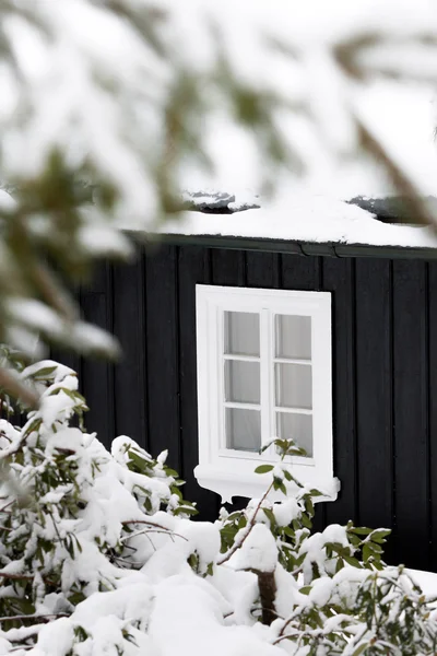 Detalhe de uma casa de madeira preta no tempo do inverno com uma janela branca — Fotografia de Stock