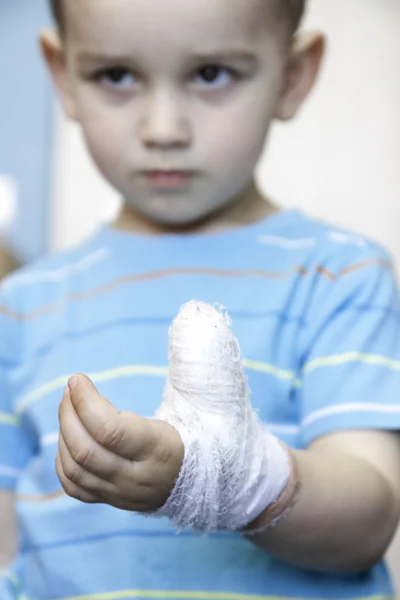 Wounded in the left hand with bandage boy at shot in home — Stock Photo, Image