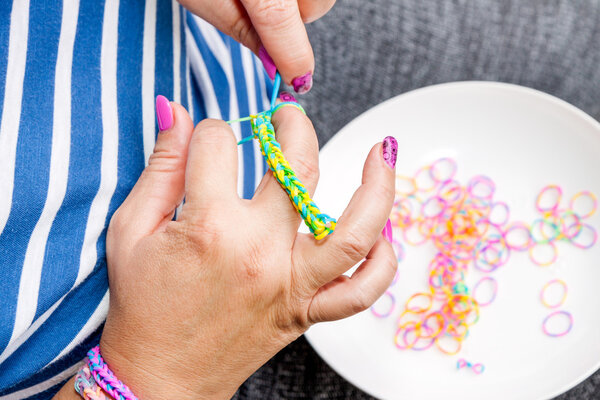 Женщины с красочными ногтями делают резиновый ткацкий станок
