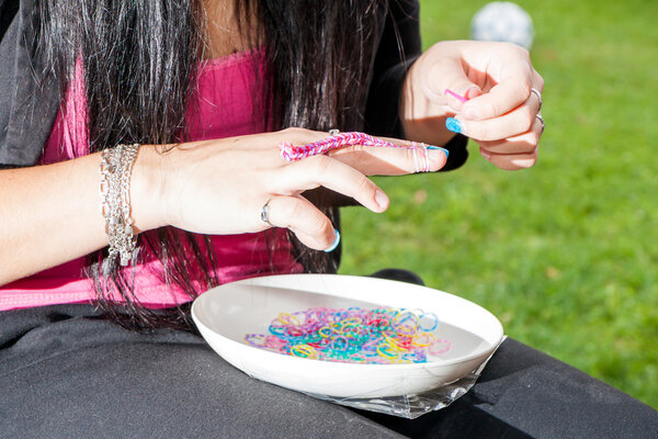 Девушка с красочными ногтями делает резиновый ткацкий станок
