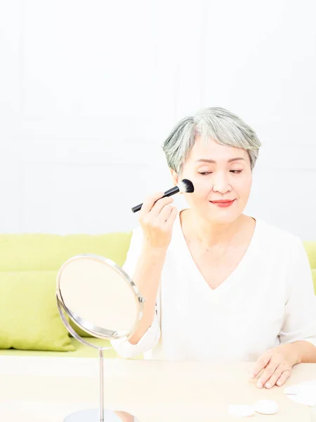 Kıdemli Asyalı Kadın Aynanın Karşısında Tek Başına Otururken Makyaj Fırçasıyla — Stok fotoğraf