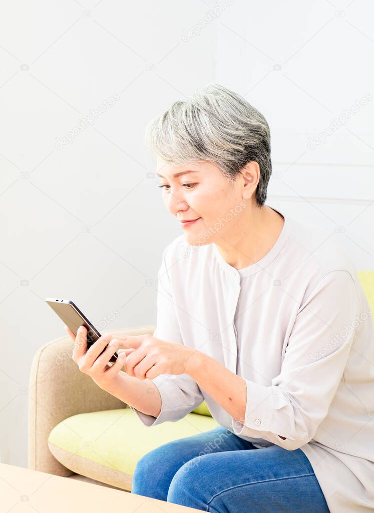 Senior asian woman holding smartphone using mobile online apps.
