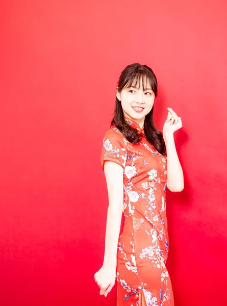 Beauty young woman wear cheongsam and hold mini heart in chinese new year on red background.