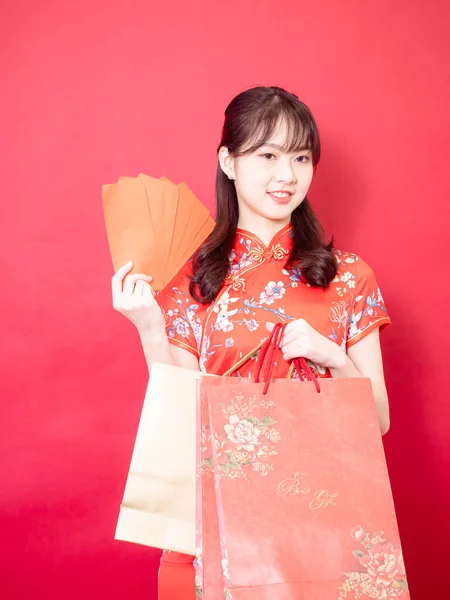 美しい若いアジアの女性を身に着けている伝統的なChongsam Qipaoドレスで赤封筒とギフトバッグで中国の旧正月のコンセプト上の赤の背景 — ストック写真