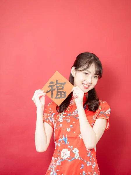 伝統的なチョンサムQipaoドレスを着た若いアジアの女性は 赤の背景に中国の文字 幸福を意味するFu で新年を祝うために中国の祭りの連句を保持しています — ストック写真