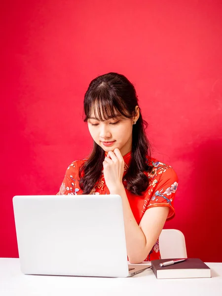 一个身穿传统旗袍的年轻亚洲女人的画像 她穿着红色背景的笔记本电脑 — 图库照片