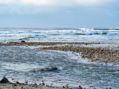 Kumsal, kum ve kayalarla dolu.