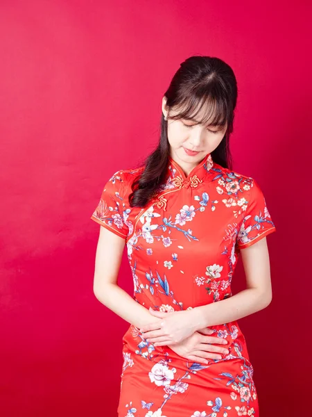 若いアジアの女性の肖像画伝統的なChongsam Qipaoドレス胃の痛みが赤い背景に隔離されている — ストック写真