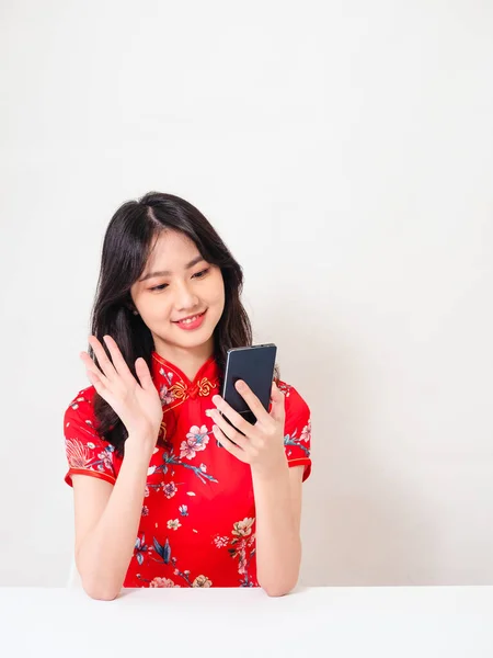身穿传统旗袍的笑着年轻的亚洲女人正在使用电话应用程序进行视频通话 在网上与白人背景隔离 — 图库照片