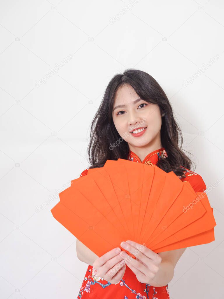 Portrait of Young asian woman wearing traditional cheongsam qipao dress with red envelopes in chinese new year on white background.