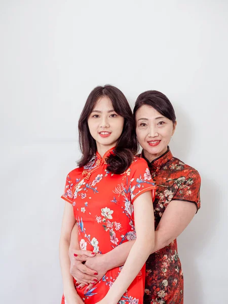 Beyaz arka planda Asyalı kızıyla kucaklaşan olgun Asyalı annenin portresi.).