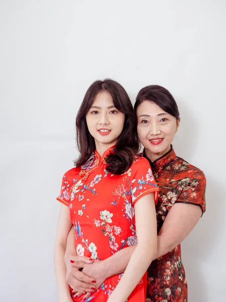 Beyaz arka planda Asyalı kızıyla kucaklaşan olgun Asyalı annenin portresi.).