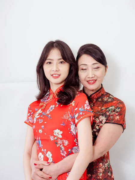 Beyaz arka planda Asyalı kızıyla kucaklaşan olgun Asyalı annenin portresi.).