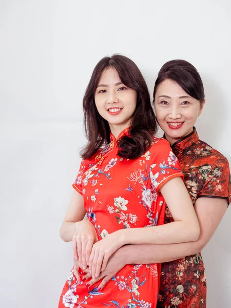 Beyaz arka planda Asyalı kızıyla kucaklaşan olgun Asyalı annenin portresi.).