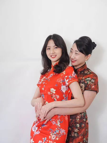 Beyaz arka planda Asyalı kızıyla kucaklaşan olgun Asyalı annenin portresi.).