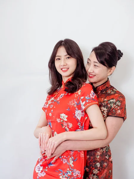 Beyaz arka planda Asyalı kızıyla kucaklaşan olgun Asyalı annenin portresi.).