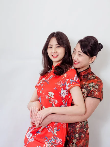 Beyaz arka planda Asyalı kızıyla kucaklaşan olgun Asyalı annenin portresi.).