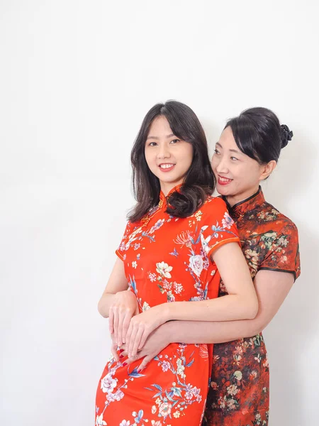 Beyaz arka planda Asyalı kızıyla kucaklaşan olgun Asyalı annenin portresi.).