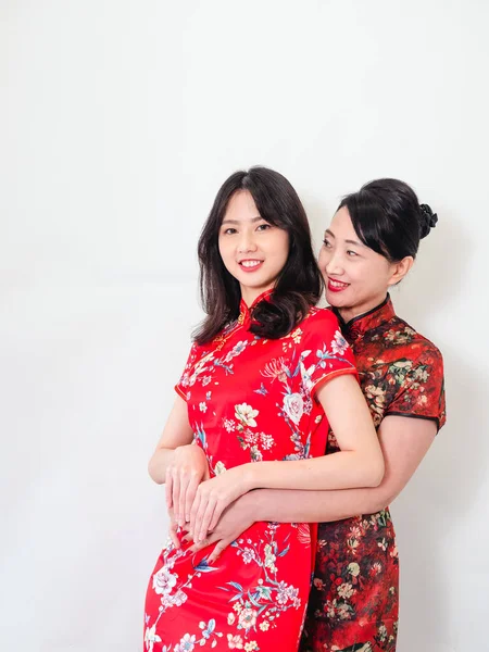 Beyaz arka planda Asyalı kızıyla kucaklaşan olgun Asyalı annenin portresi.).