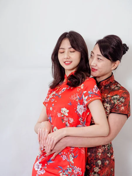 Beyaz arka planda Asyalı kızıyla kucaklaşan olgun Asyalı annenin portresi.).