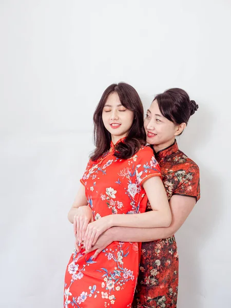 Beyaz arka planda Asyalı kızıyla kucaklaşan olgun Asyalı annenin portresi.).