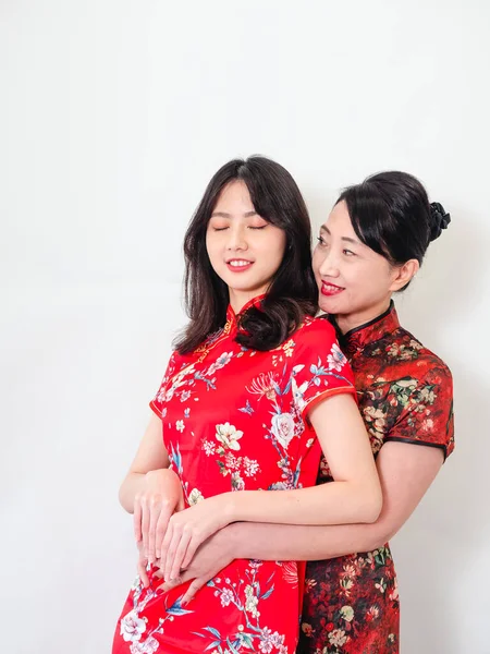 Beyaz arka planda Asyalı kızıyla kucaklaşan olgun Asyalı annenin portresi.).