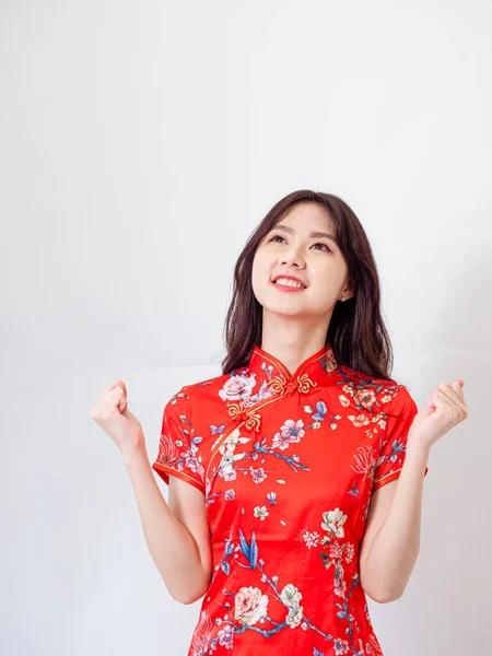 Portrait of young asian woman wearing traditional cheongsam qipao dress over isolated white background holding copyspace with two hands.