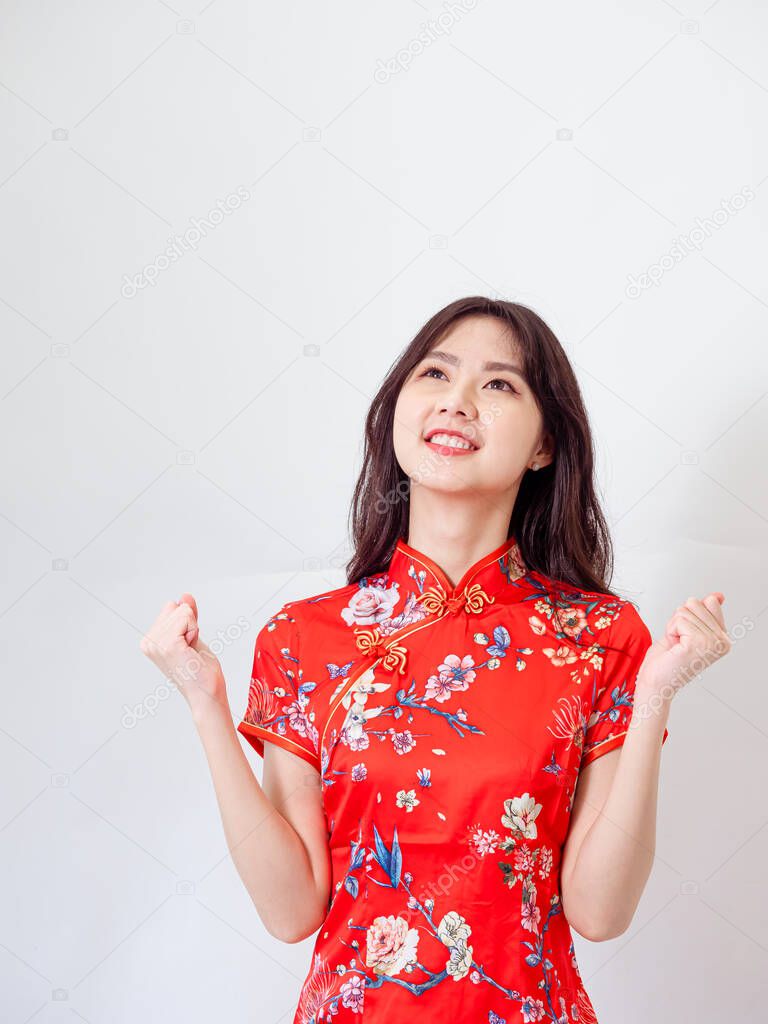 Portrait of young asian woman wearing traditional cheongsam qipao dress over isolated white background holding copyspace with two hands.