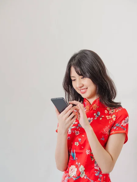一个年轻的亚洲女人穿着传统旗袍 穿着白色背景的智能手机的肖像 — 图库照片