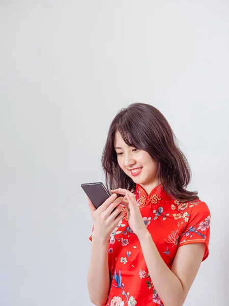 一个年轻的亚洲女人穿着传统旗袍 穿着白色背景的智能手机的肖像 — 图库照片