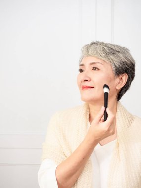 Ellerinde makyaj fırçası olan 50 'li yaşlarda Asyalı bir kadının portresi..