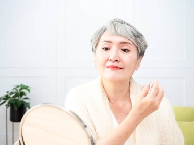 Olgun Asyalı kadın portresi 60 'lı yaşlarda parfüm sıkar..