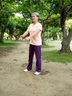 60 'ların yaşlı, yaşlı Asyalı kadının portresi. Havlu üstüne havluyla ayakta duruyor ve parkta temiz havanın tadını çıkarıyor..
