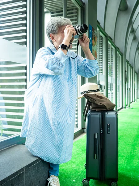 Mutlu yetişkin yaşlı Asyalı kadının portresi. 60 'lı yaşlarda seyahat konsepti için fotoğraf makinesiyle fotoğraf çekiyor..