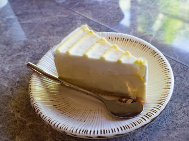 Masadaki tatlı tabakta. Sarı limon şuruplu klasik cheesecake..