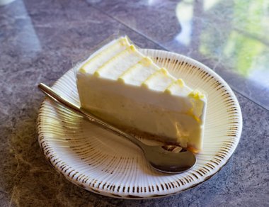 Masadaki tatlı tabakta. Sarı limon şuruplu klasik cheesecake..