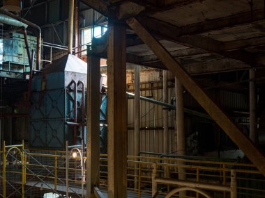 Boruları ve paslı metal yapıları olan terk edilmiş bir fabrikanın içini.